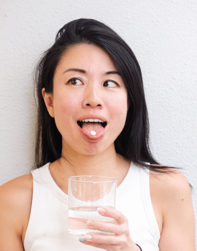 woman with toothpaste tab on tongue