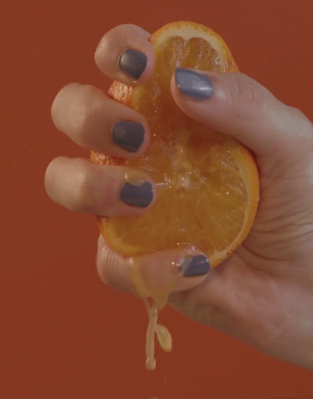 hand squeezing orange fruit