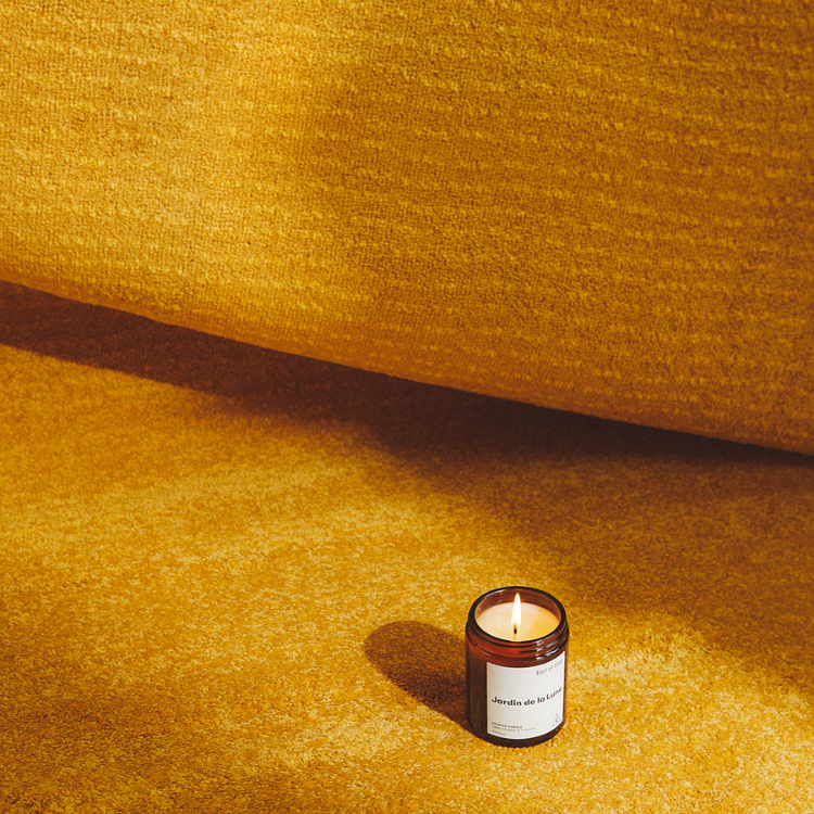 lighted Jardin De La Lune Soy Candle on a carpet