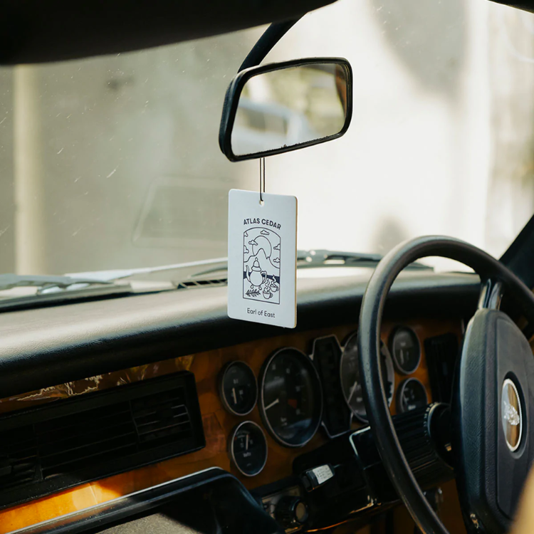 Atlas Cedar Air Freshener hanging by a car's rearview mirror