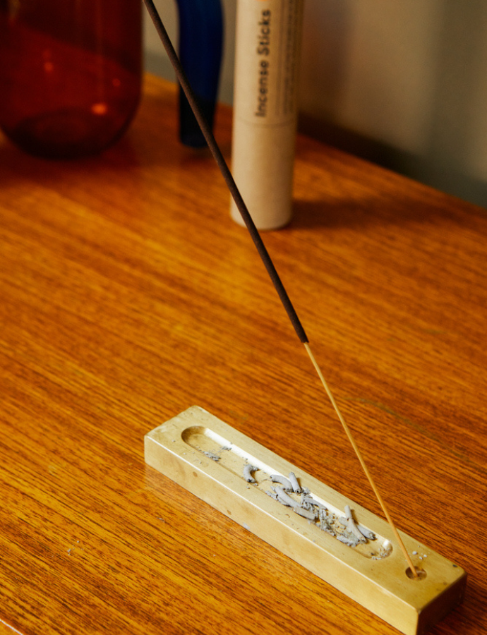 burning incense stick on a holder with ashes