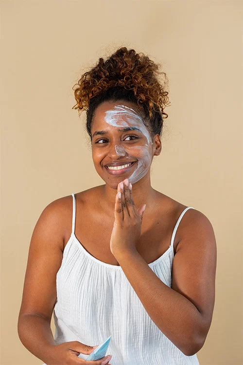 smiling woman applying hyaluronic acid mask on face