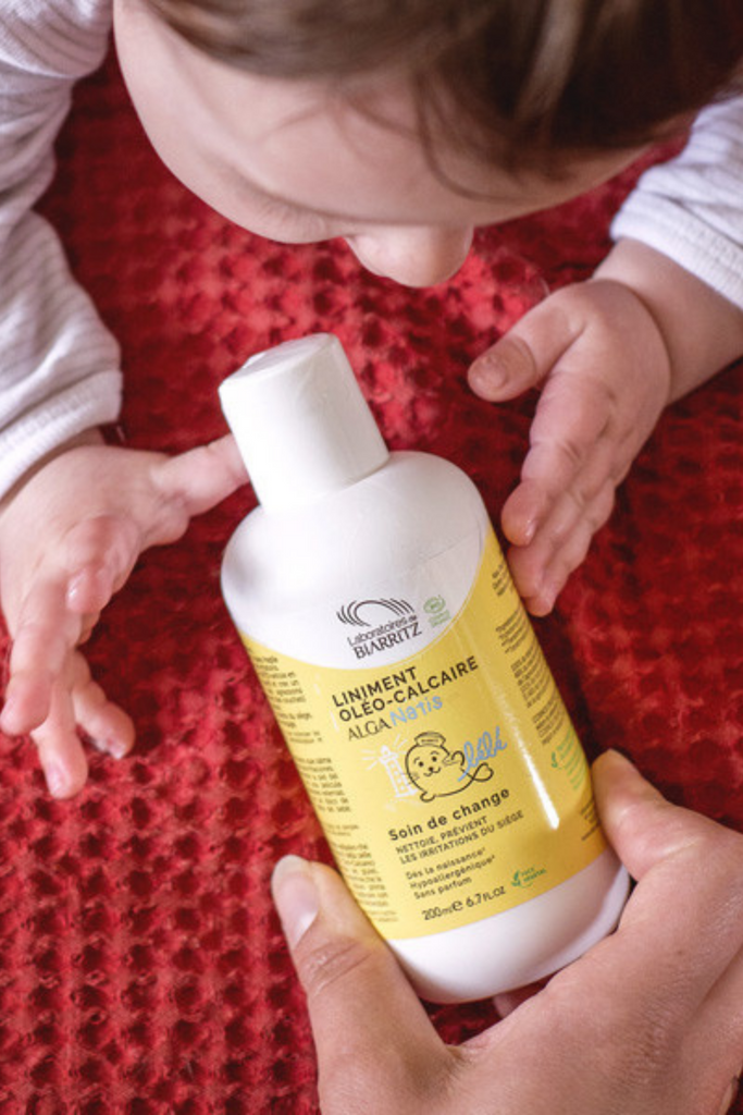 baby's hand reaching for a bottle of Organic Liniment Diaper Change Cleanser