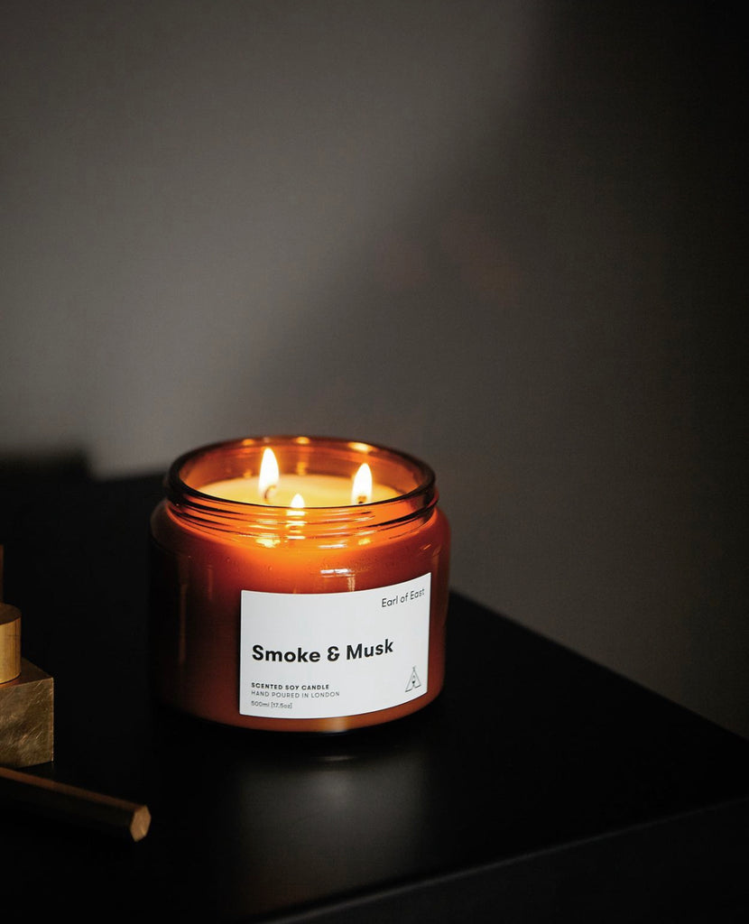 Smoke & Musk Soy Candle lighted on a bedside table